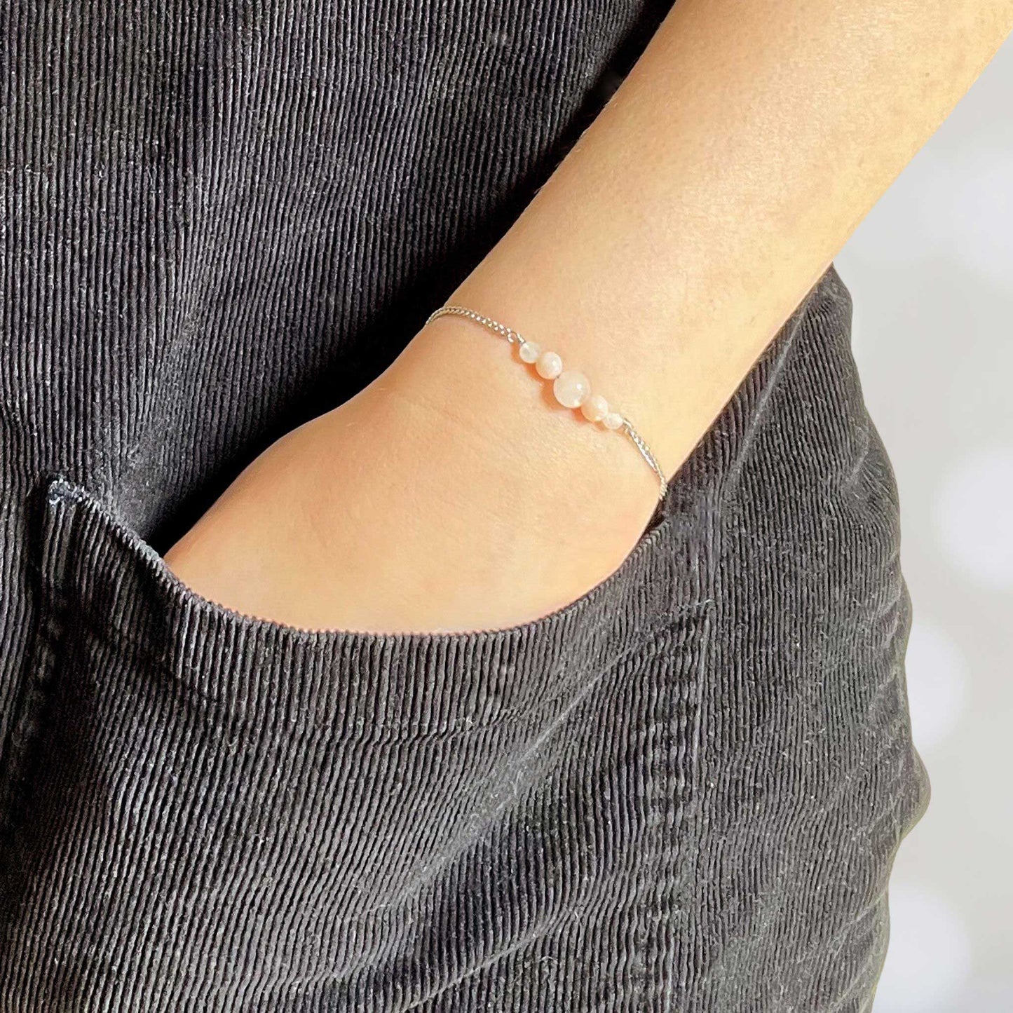 Woman with hand in pocket wearing dainty pale pink stone bracelet