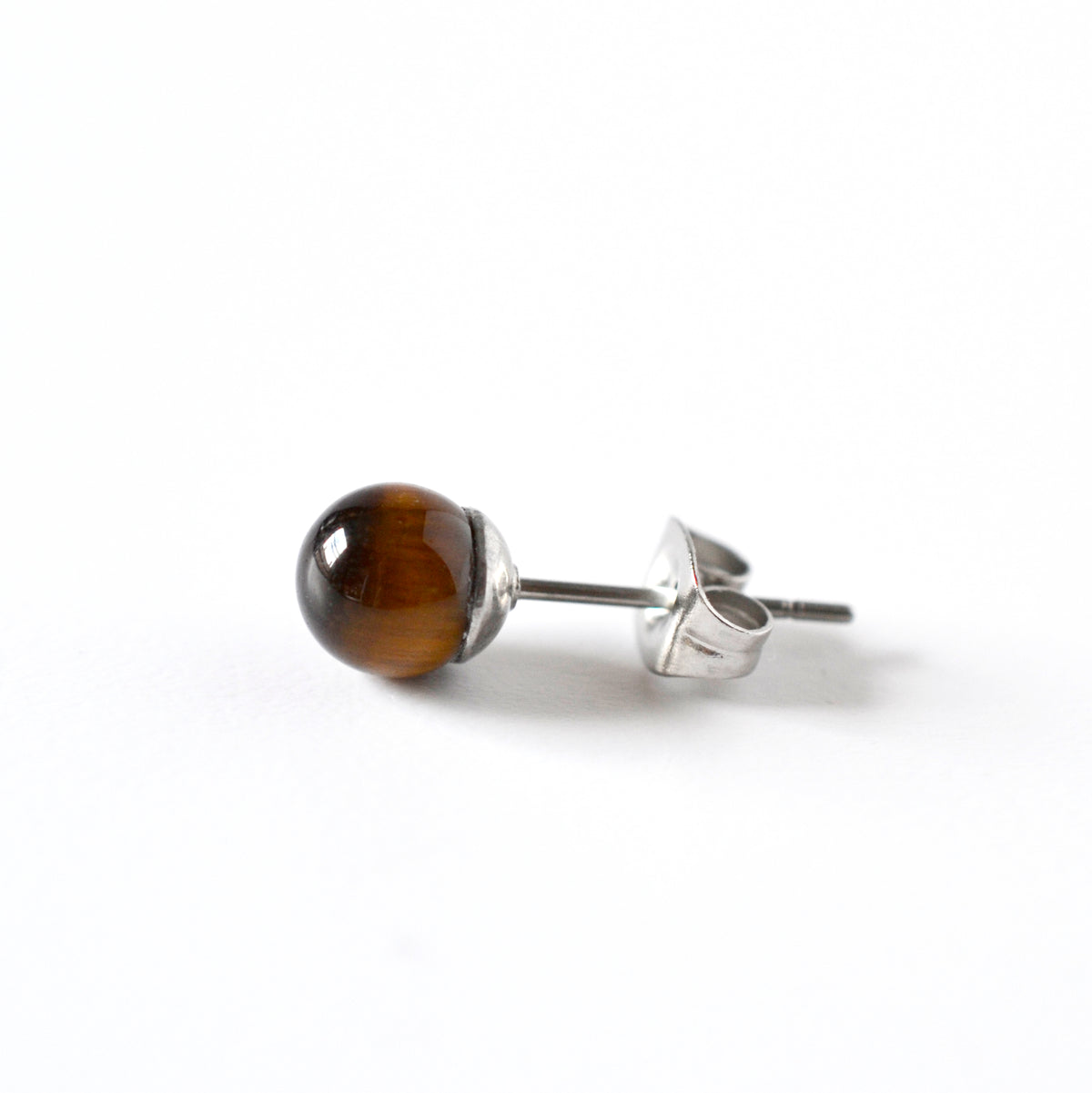 A single stud earring featuring a polished brown tiger's eye bead on a surgical steel post and butterfly back, shown on a clean white background.