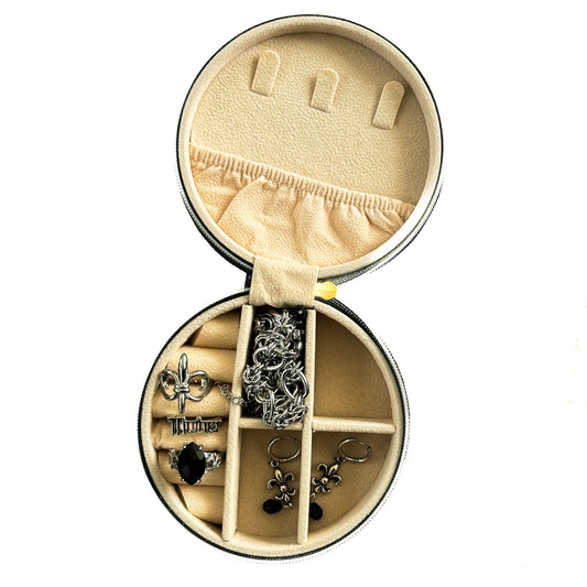 Round jewelry box with compartments containing various earrings on a white background