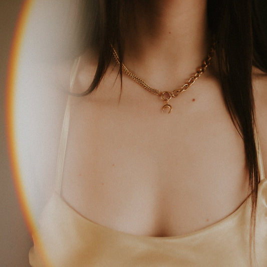 Close-up of a person wearing a gold chain necklace with a blurred background