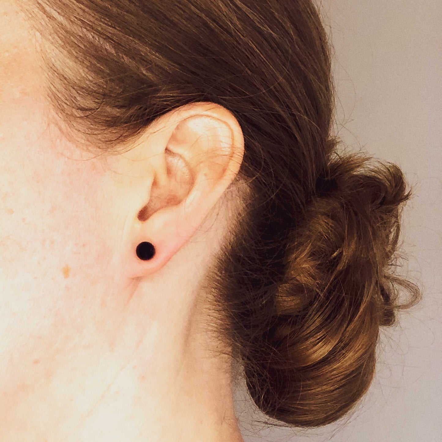 Woman wearing Sodalite stud earrings blue stone in earlobe