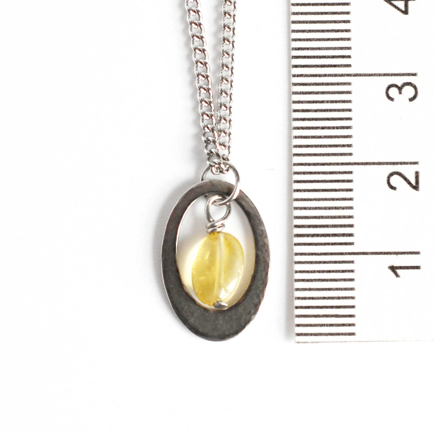 Dainty Citrine pendant necklace next to ruler.