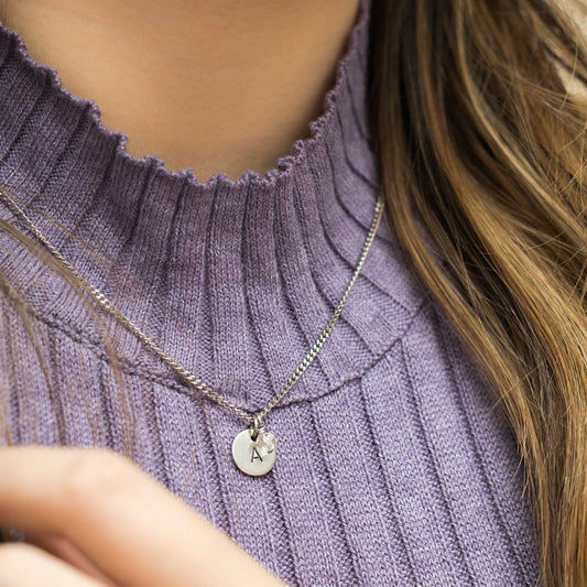 Model wearing initial birthstone necklace and purple sweater