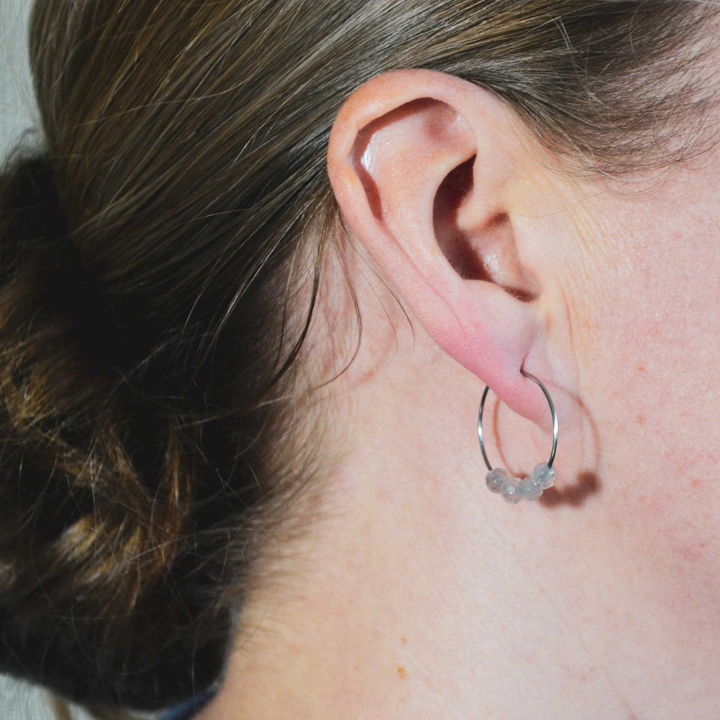 Woman wearing grey Agate gemstone hoop earrings in earlobe