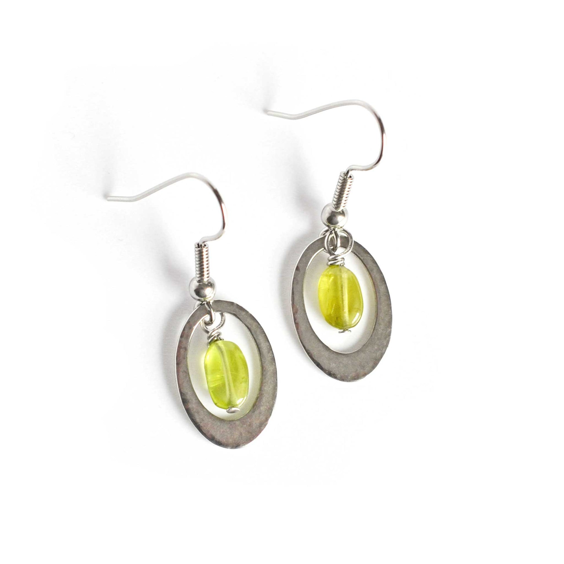 Pair of oval Peridot earrings with hypoallergenic surgical steel hooks on white background.