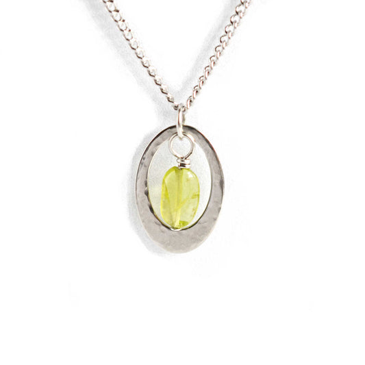 Dainty oval Peridot necklace with stainless steel curb chain on white background.