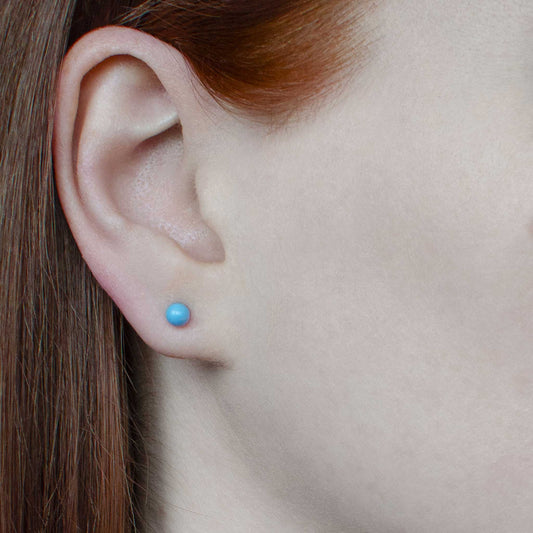 Woman with red hair tucked behind ear wearing tiny Turquoise stud earring in lobe