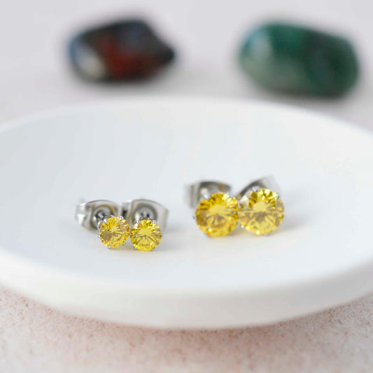 4mm & 6mm yellow CZ stud earrings in white trinket dish.