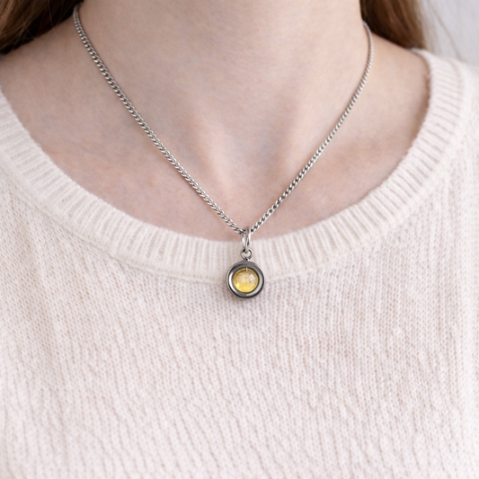 Woman wearing pale pink jumper and yellow Citrine spinner necklace.