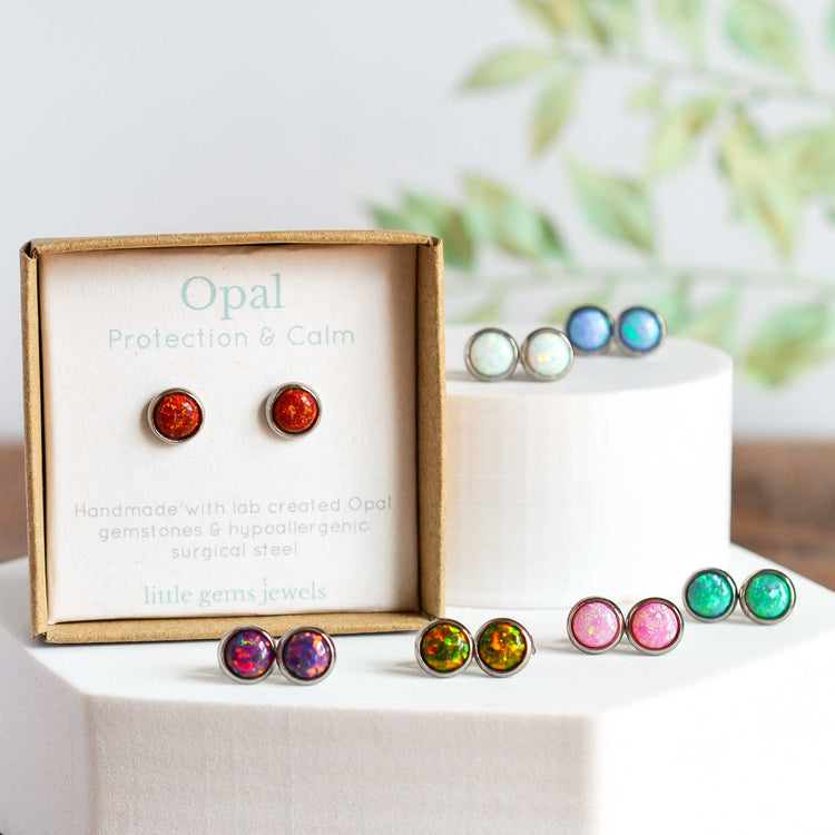 Seven different coloured lab created Opal stud earrings on display plinth