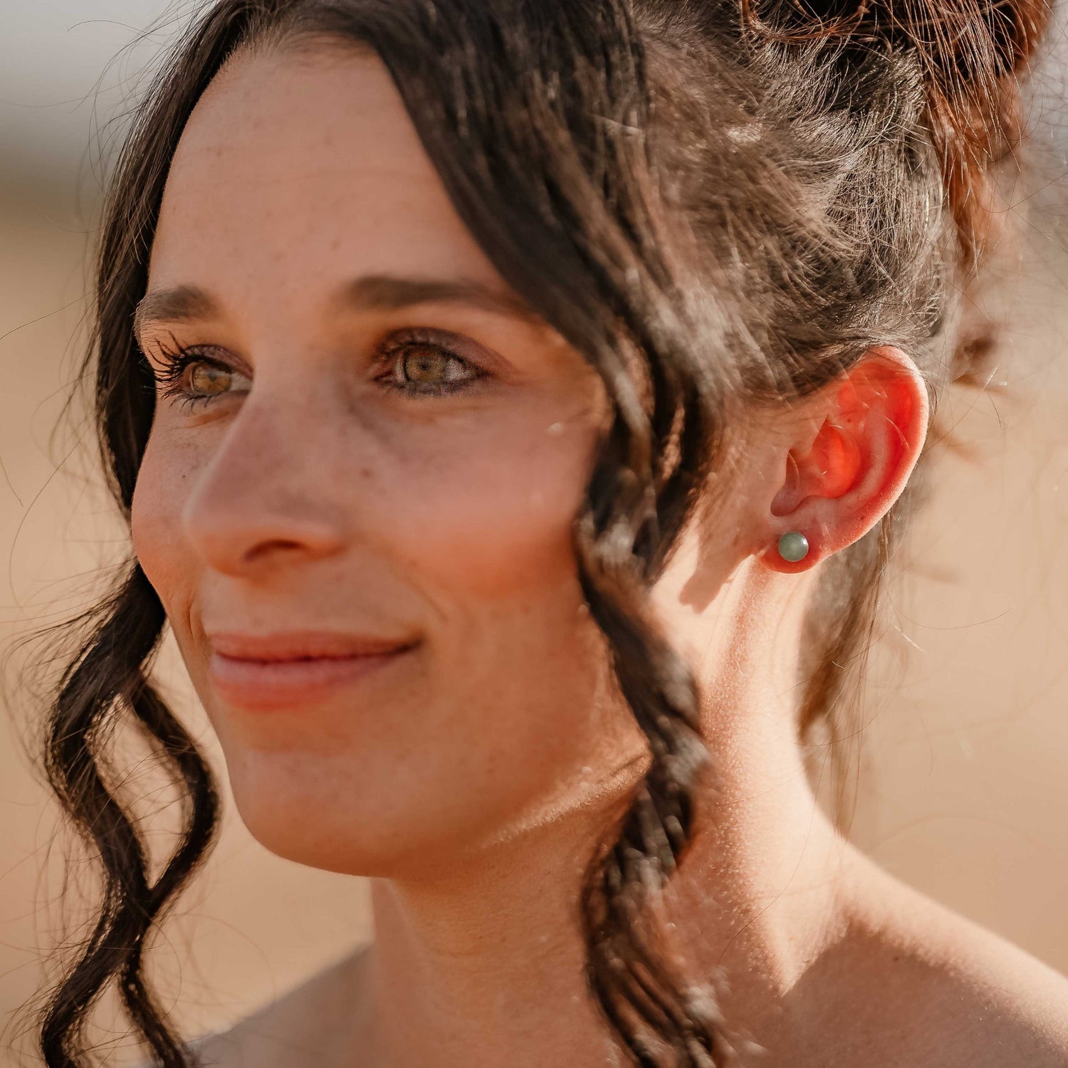 Smiling woman with long brown hair wearing natural green gemstone stud earring