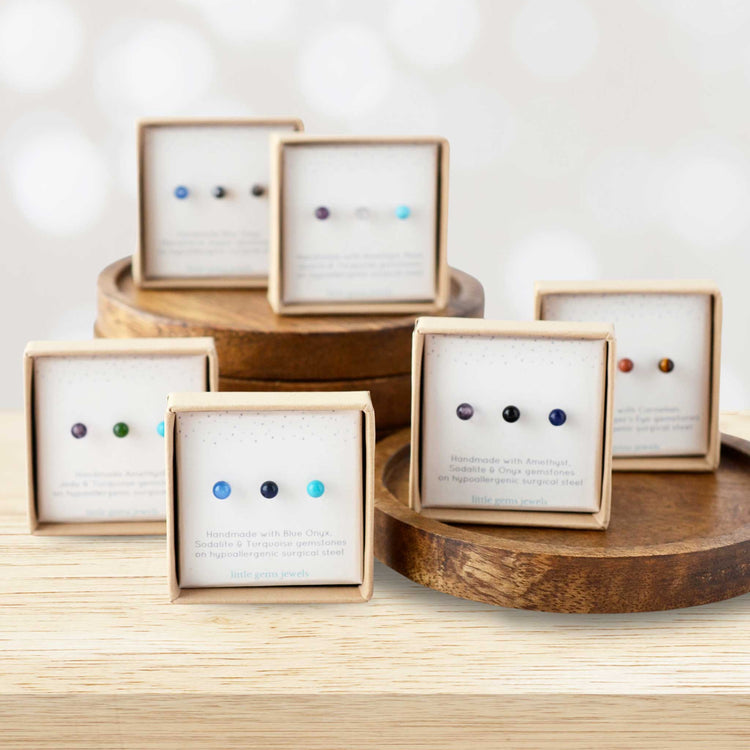 Sets of three single gemstone stud earrings in eco friendly gift boxes stacked on wooden coasters