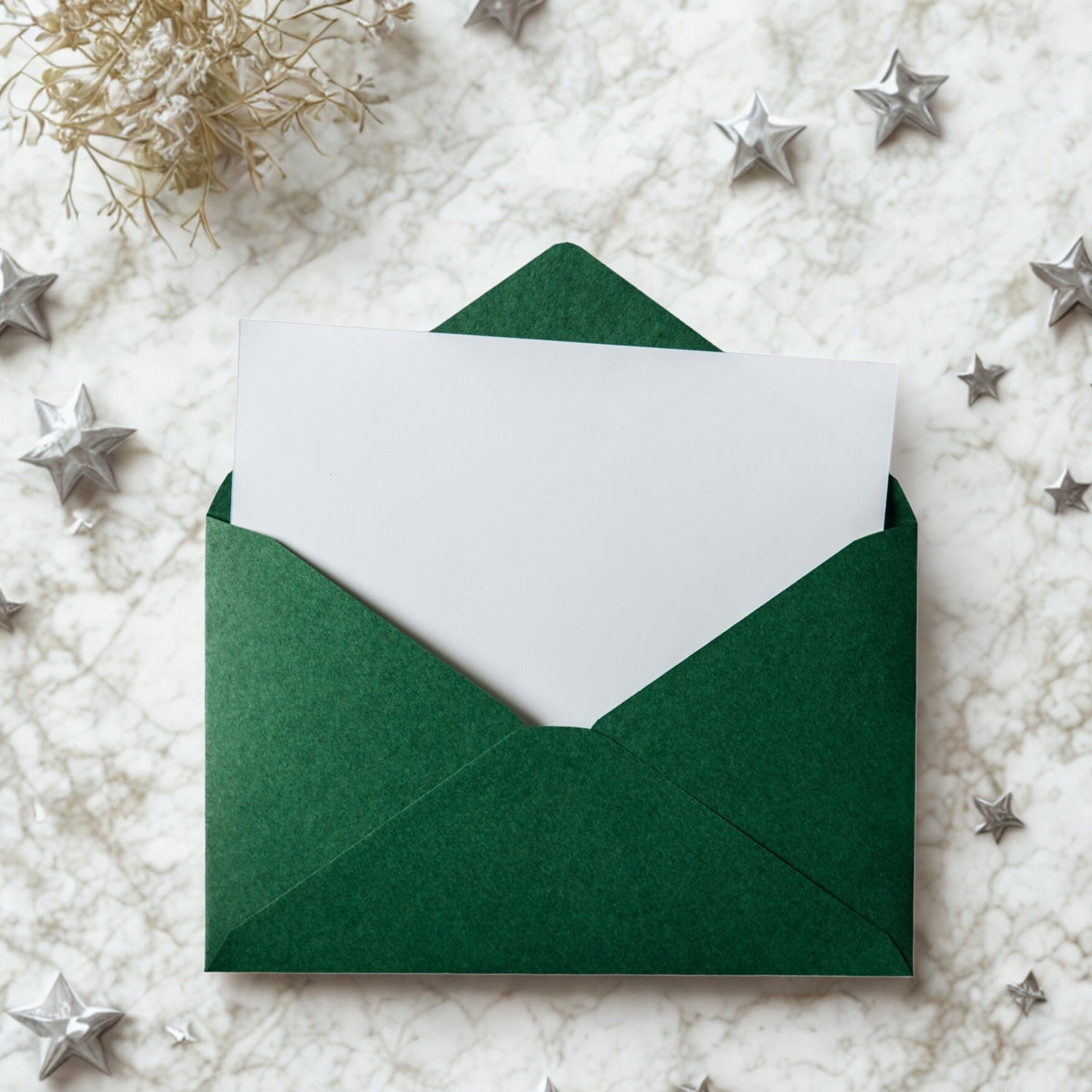 Green envelope on white marble background with silver stars