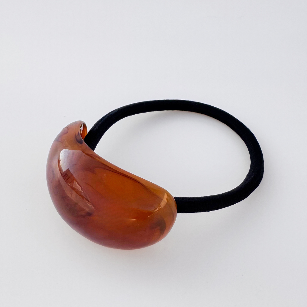 Brown hair tie with a black elastic band on a white background
