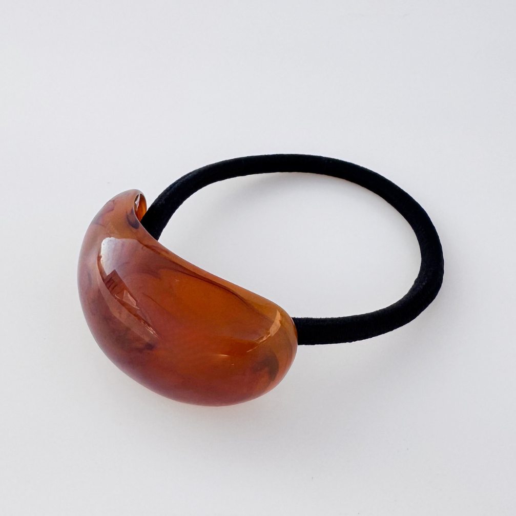 Brown hair tie with a black elastic band on a white background