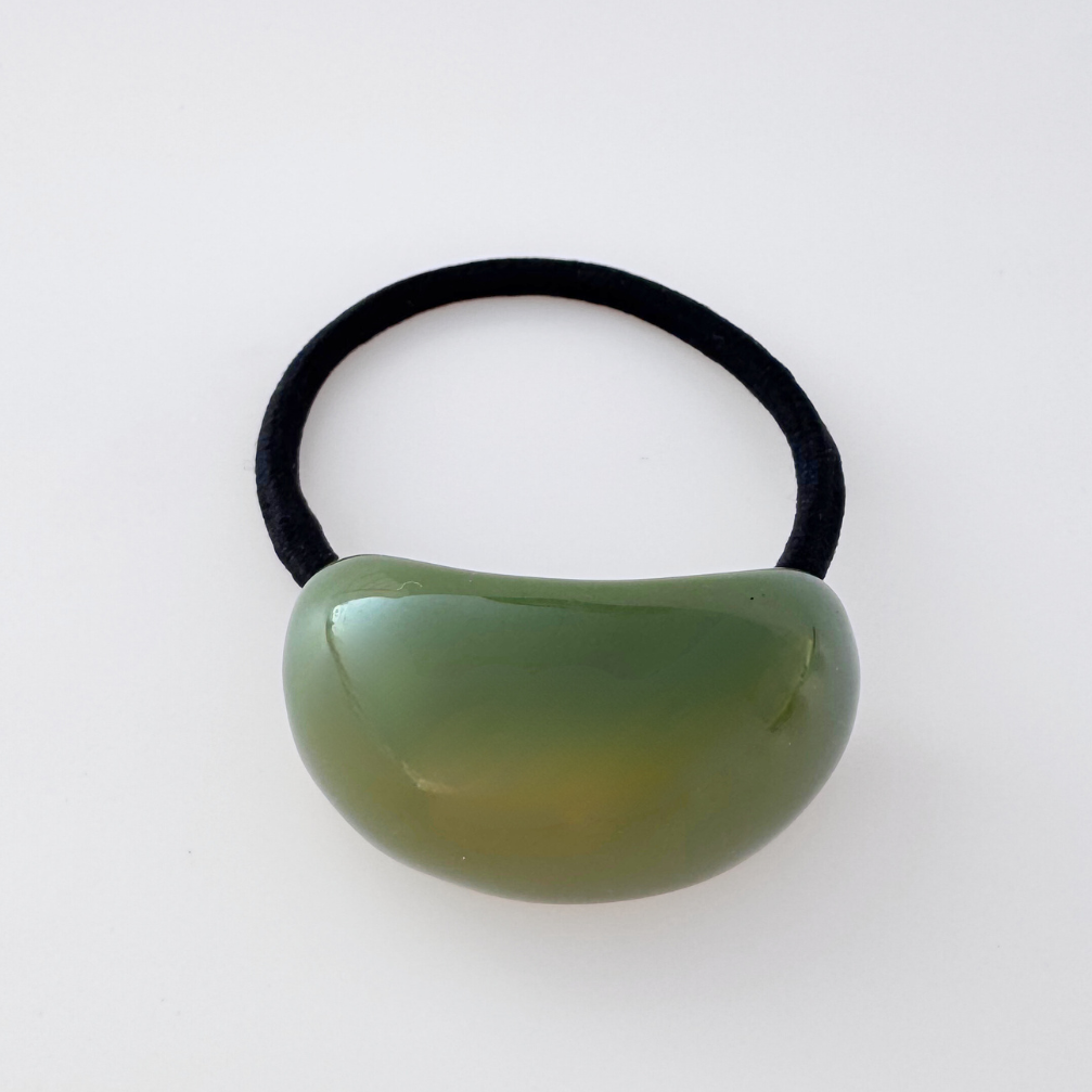 Green hair tie with a black elastic band on a white background