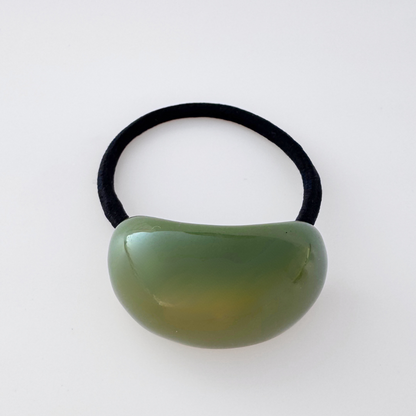 Green hair tie with a black elastic band on a white background