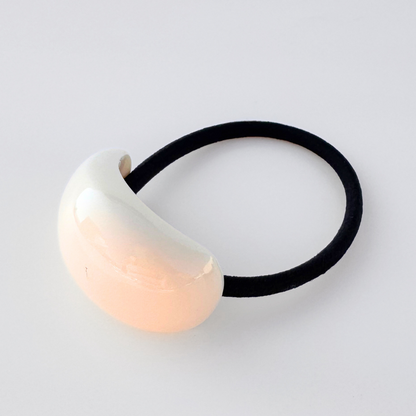 Hair tie with a cream bead on a light gray background