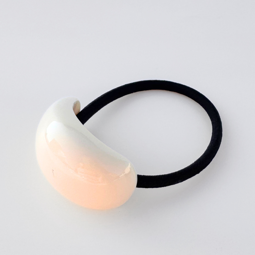 Hair tie with a white ceramic ball on a light gray background