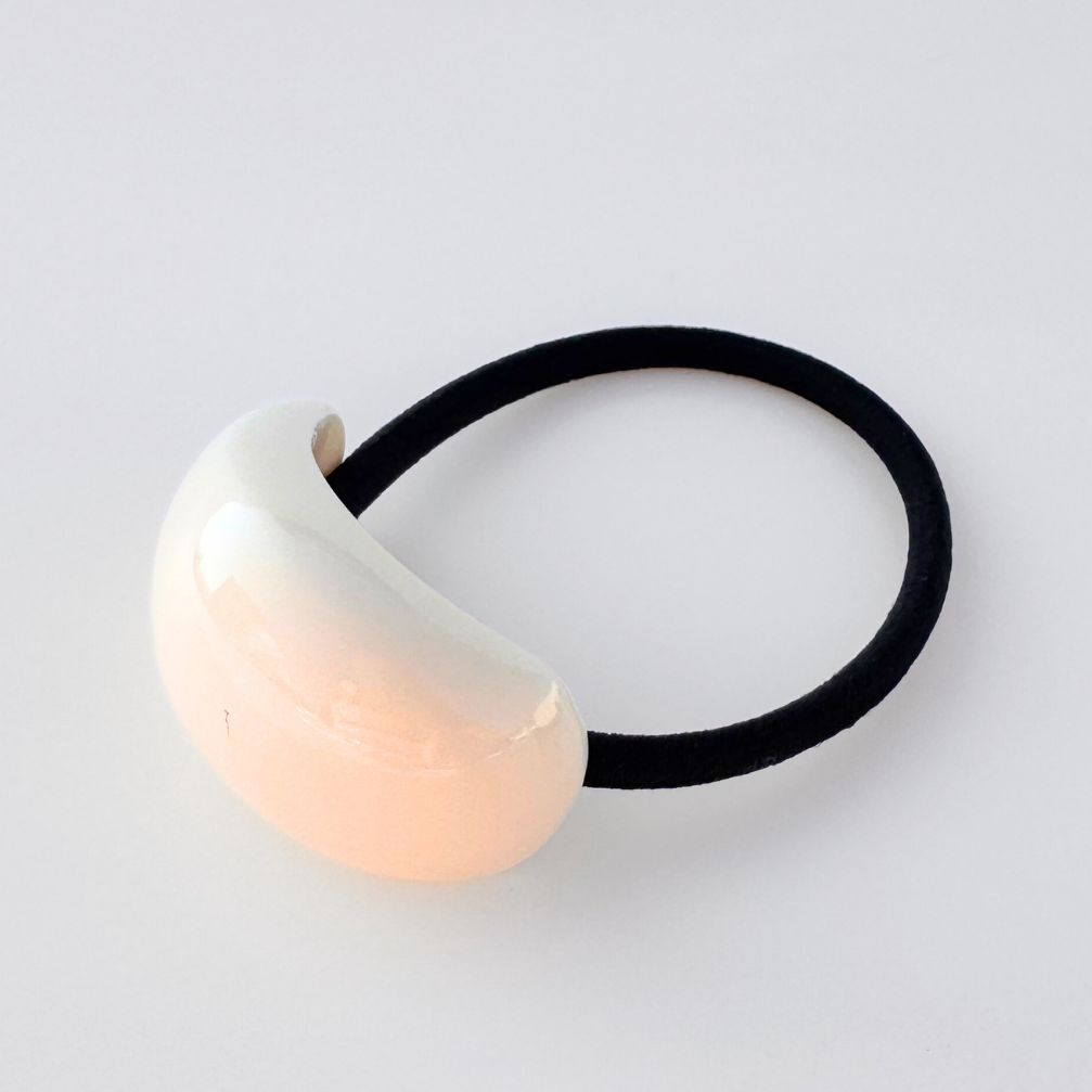 Hair tie with a cream bead on a light gray background