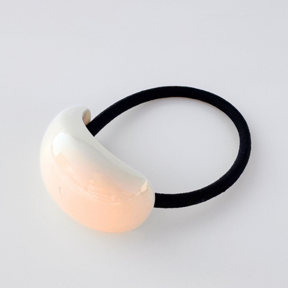 Hair tie with a cream bead on a light gray background