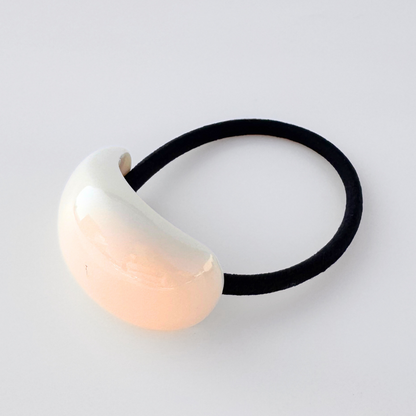 Hair tie with a cream ceramic ball on a light gray background
