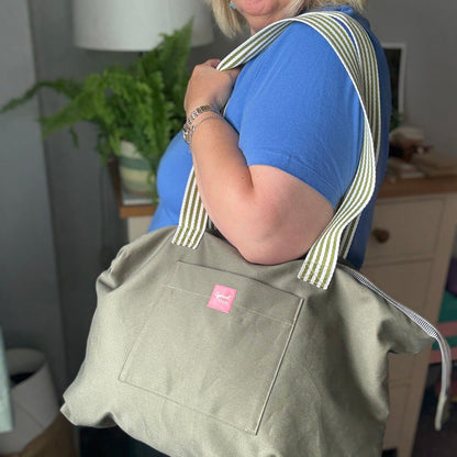 Person holding a green bag with a pink label in an indoor setting