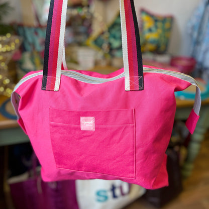 Pink tote bag with a visible brand logo on a blurred background