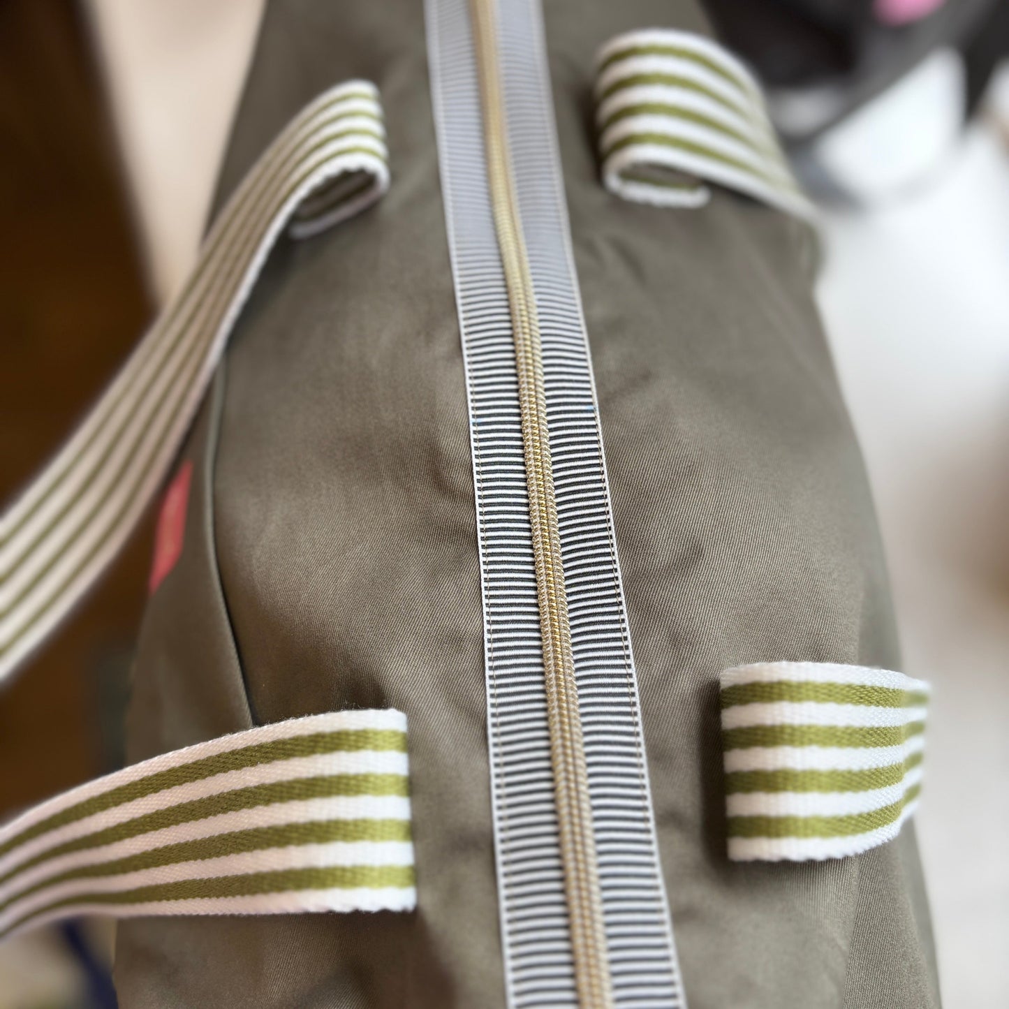 Close-up of a green jacket with striped trim and buttons.