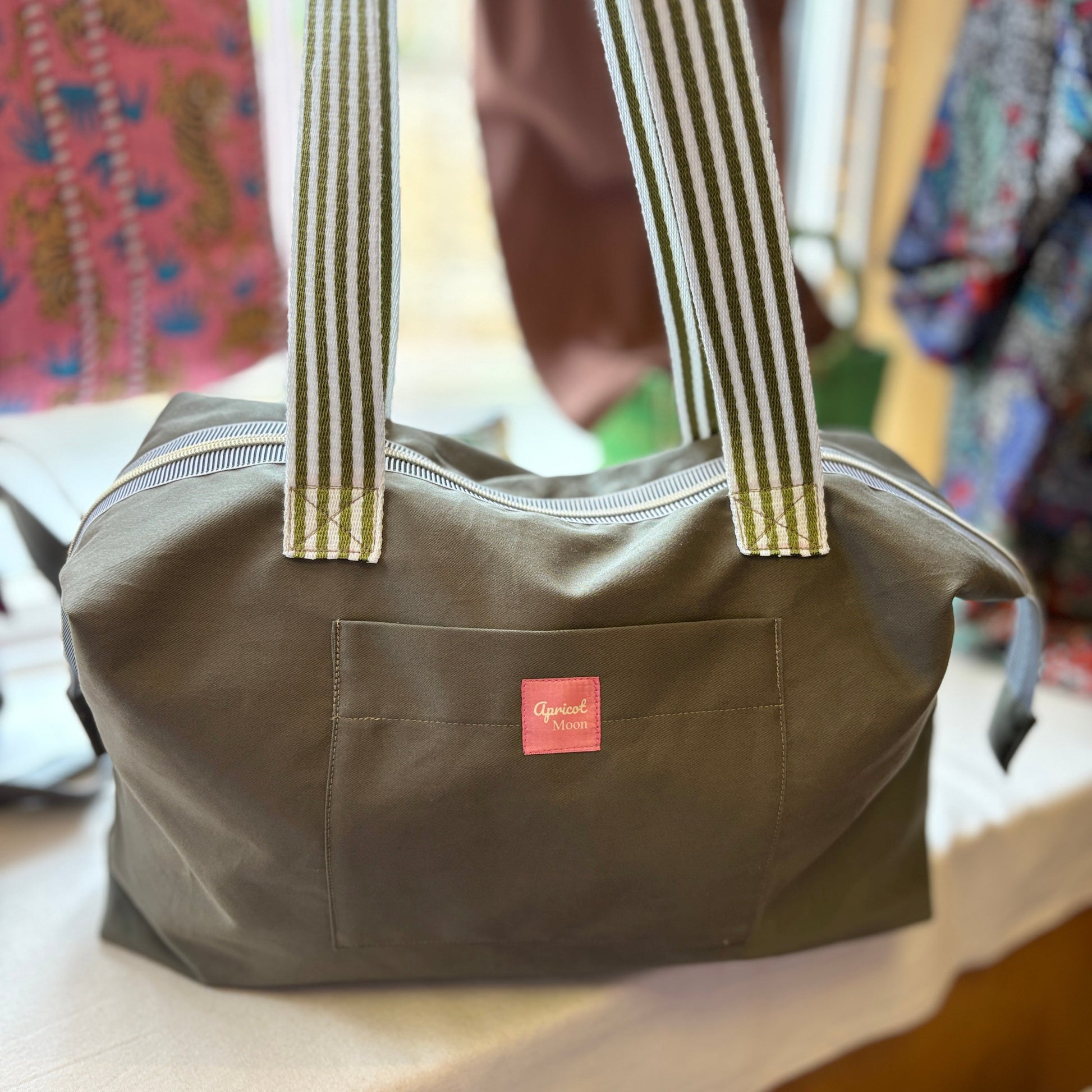 Green bag with striped handles on a table with a colorful background