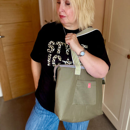 Woman holding a green bag indoors with wooden and white doors in the background