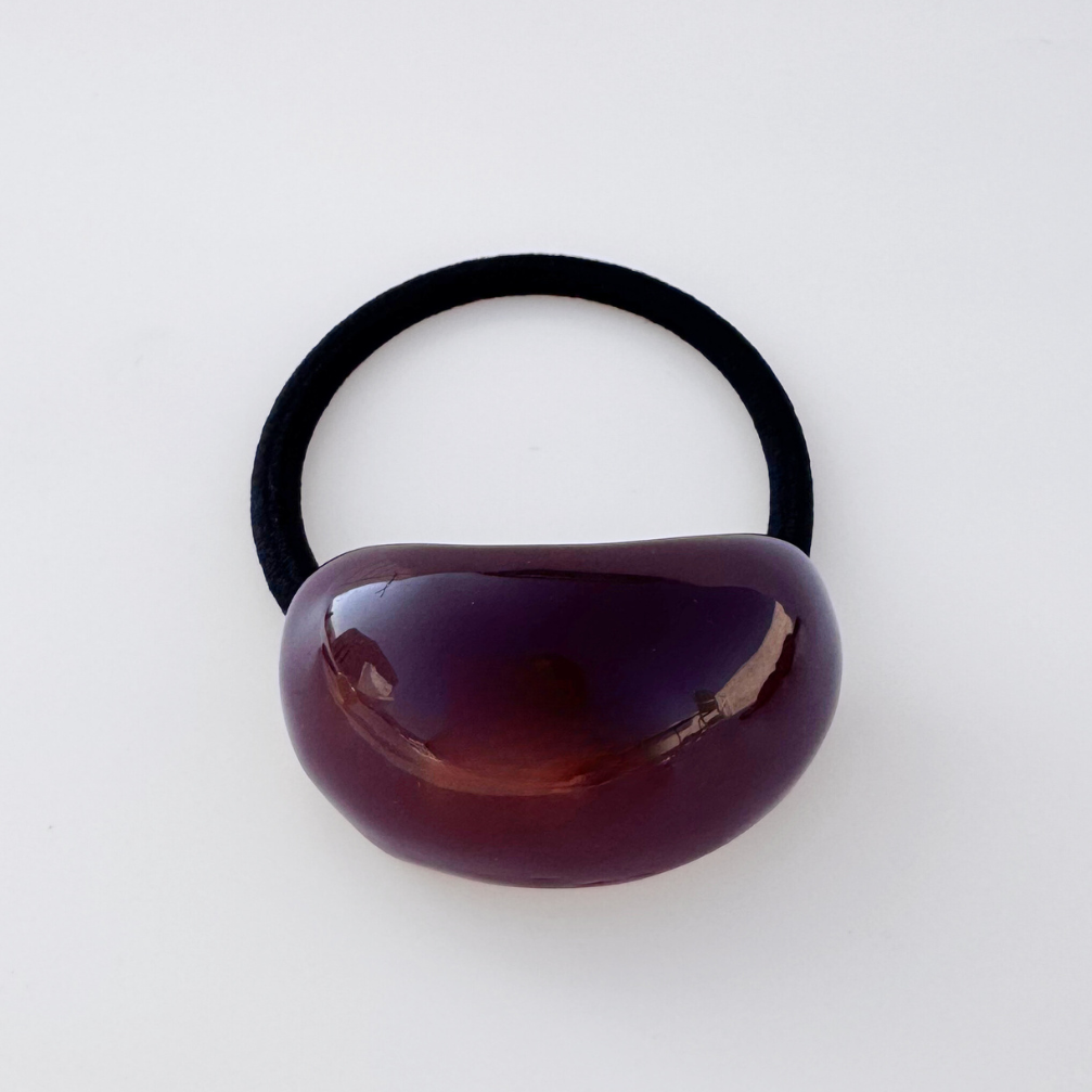 Black hair tie with a brown oval grip on a white background