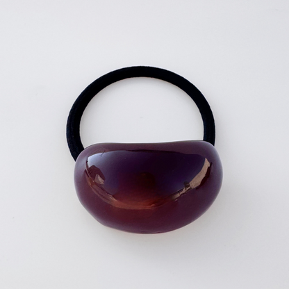 Black hair tie with a brown bead on a white background