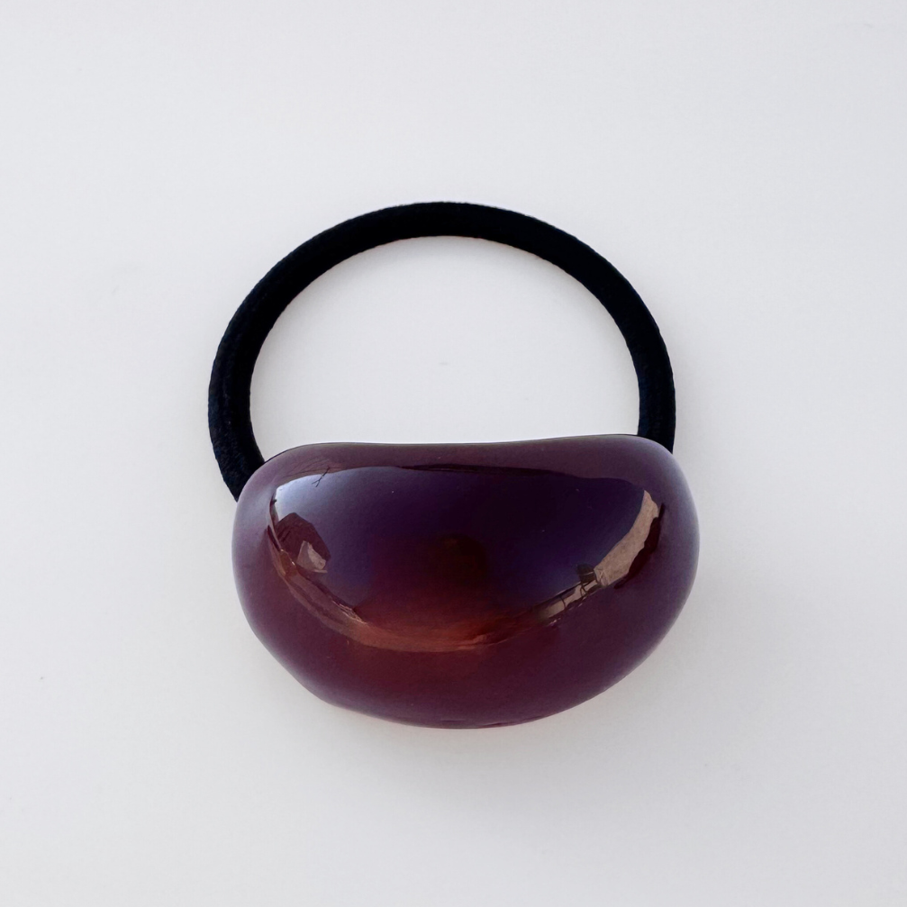 Black hair elastic with a brown plastic bead on a white background