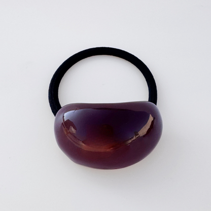 Black hair elastic with a brown plastic bead on a white background