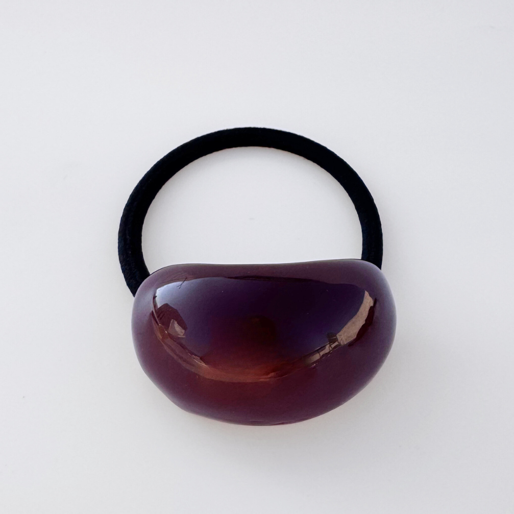 Black hair elastic with a brown bead on a white background