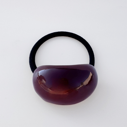 Black hair elastic with a brown bead on a white background