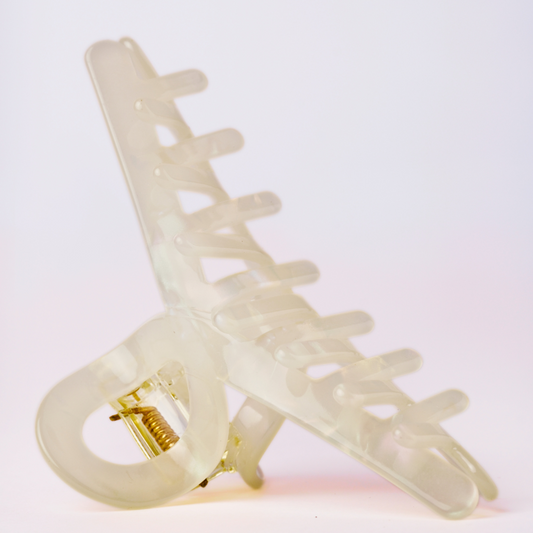 Cream plastic hair clip on a light pink background