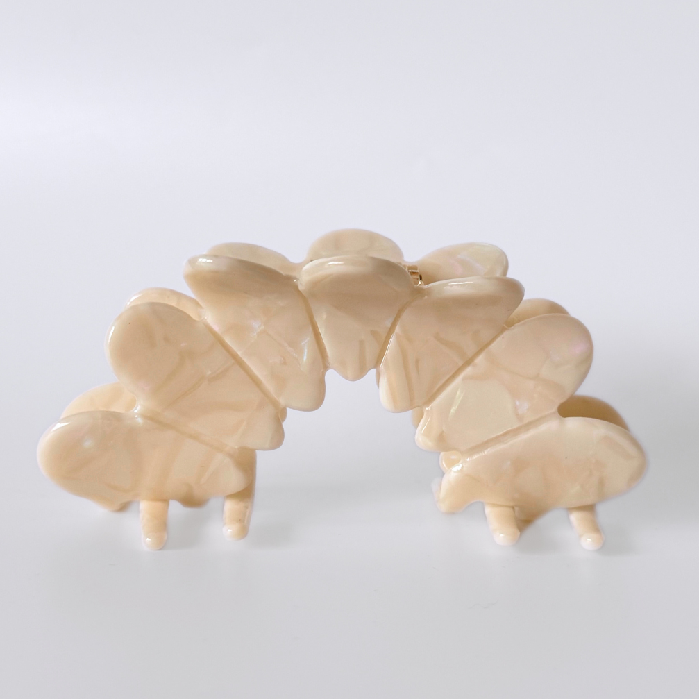 Beige hair clip with butterfly design on a white background