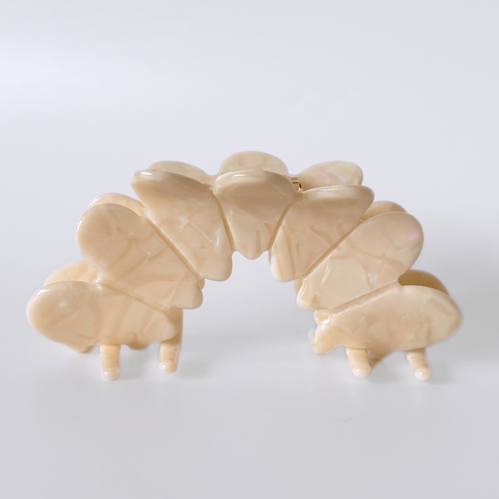 Beige hair clip with butterfly design on a white background