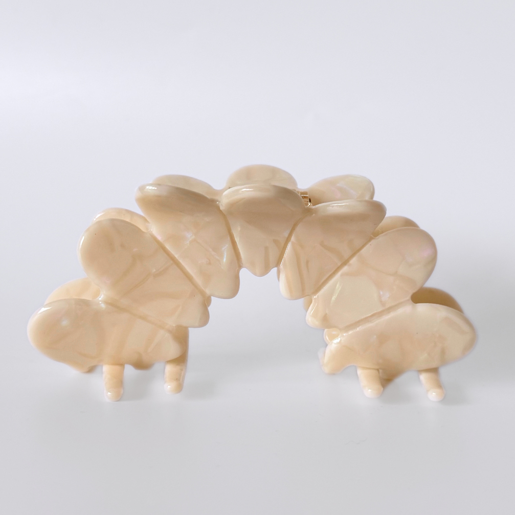 Beige hair clip with butterfly design on a white background