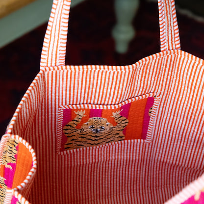 Red and white striped tote bag with a tiger design on a blurred background