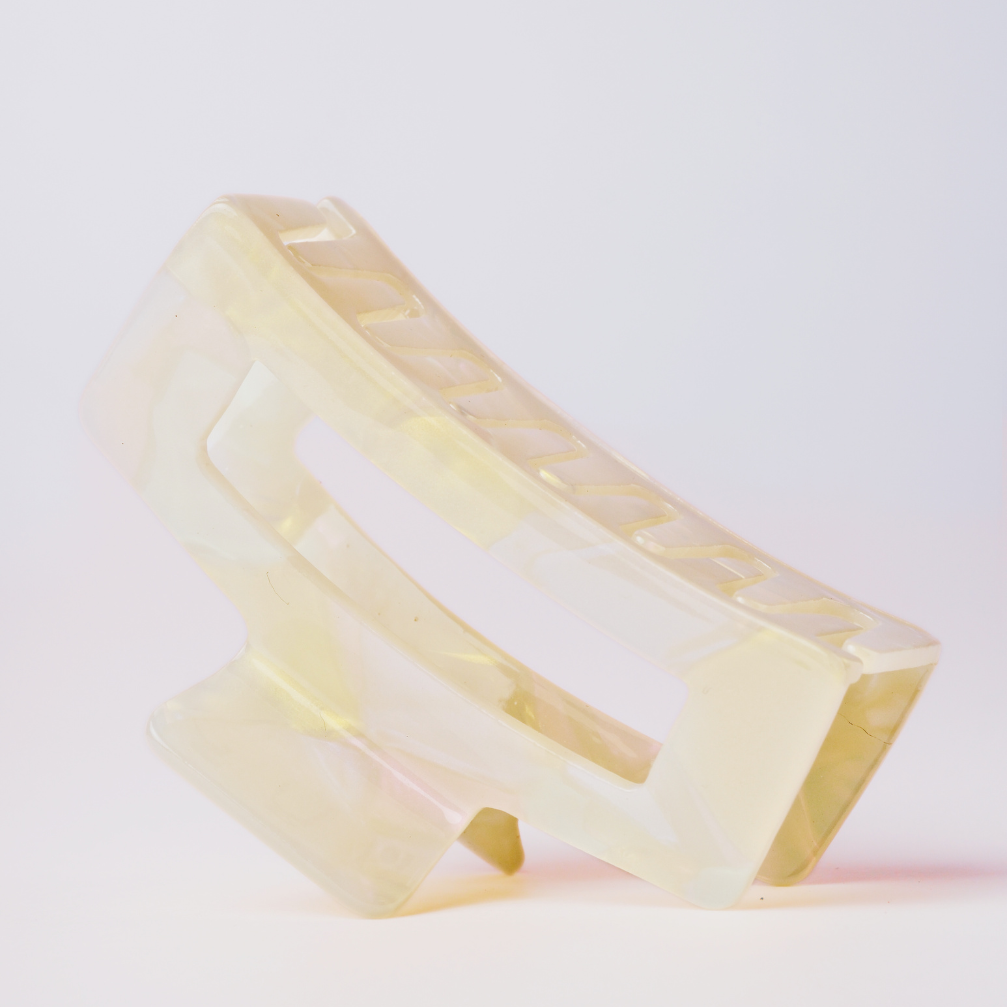 Cream hair clip with a yellow tint on a white background