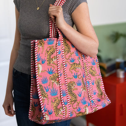 Person holding a pink tote bag with tiger pattern indoors
