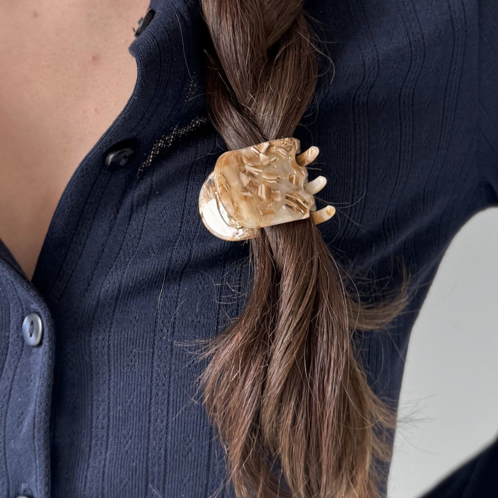 Gold hair clip in a braid with a person wearing a dark blue shirt.