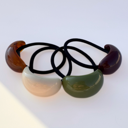 Set of four hair ties with colorful plastic ends on a white background