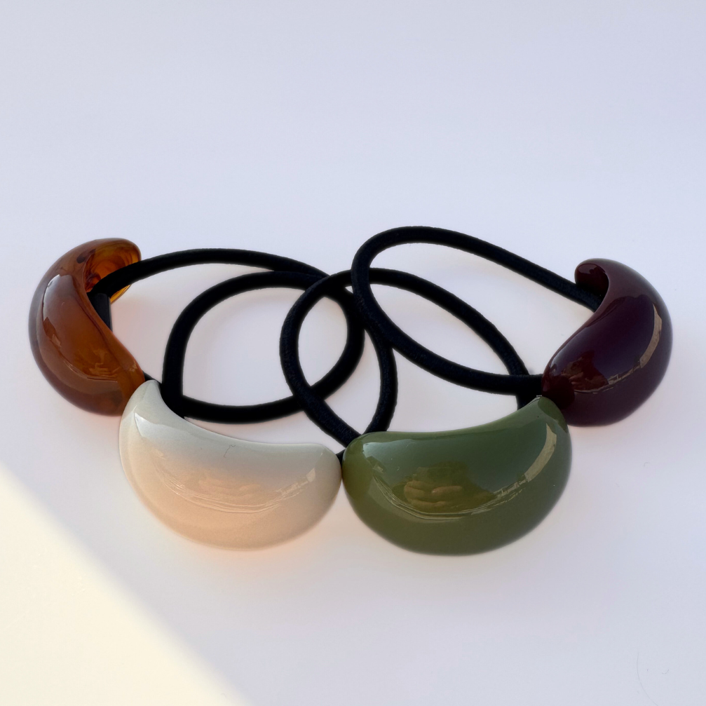 Set of four hair ties with colorful plastic ends on a white background