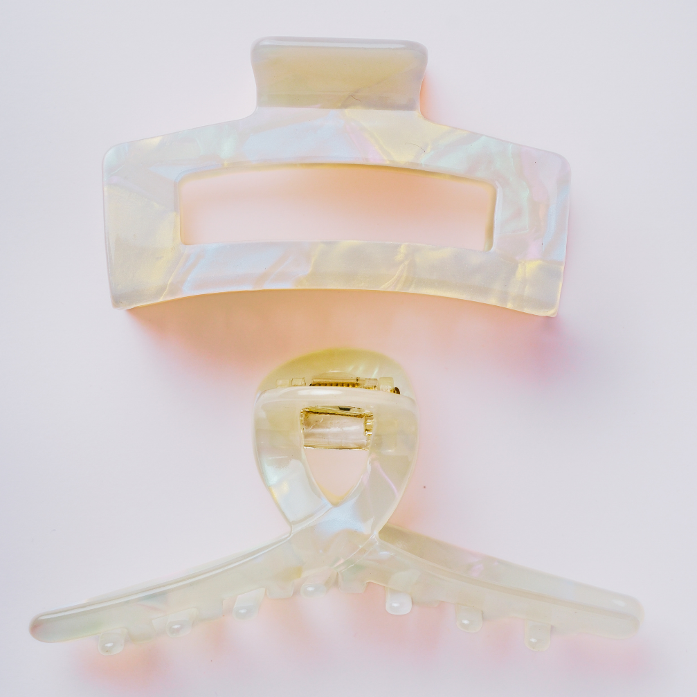 Decorative hair clips with a soft pink and gold gradient on a light pink background