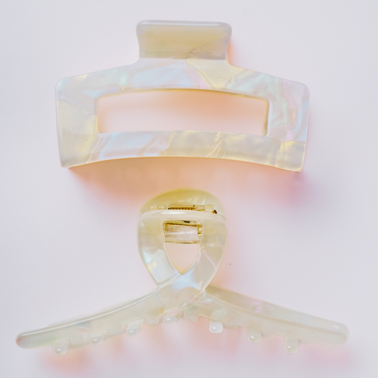 Decorative hair clips with a soft pink and gold gradient on a light pink background