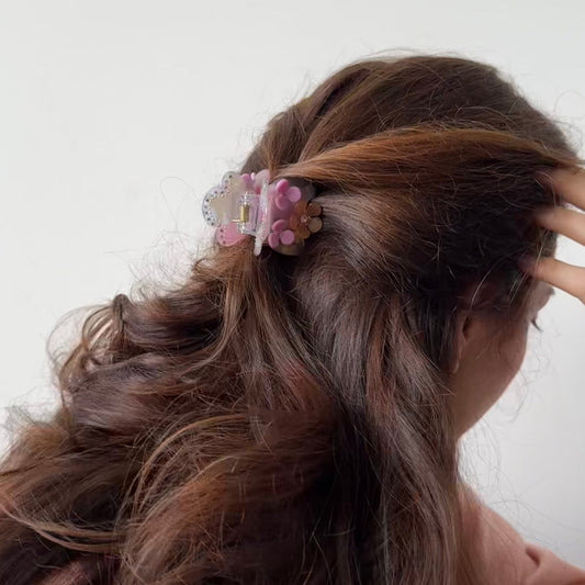 Person with wavy hair wearing a decorative hair clip against a white background